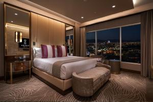 a bedroom with a bed and a chair and windows at SAHARA Las Vegas in Las Vegas