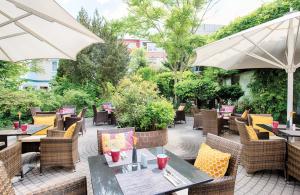 eine Außenterrasse mit Tischen, Stühlen und Sonnenschirmen in der Unterkunft Leonardo Hotel Heidelberg City Center in Heidelberg