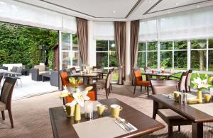 un restaurant avec des tables, des chaises et des fenêtres dans l'établissement Leonardo Hotel Aachen, à Aix-la-Chapelle