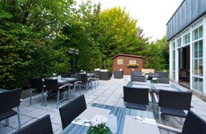 a patio with tables and chairs and a building at Leonardo Hotel Aachen in Aachen