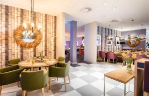 ein Restaurant mit Tischen und Stühlen und eine Bar in der Unterkunft Leonardo Hotel Wolfsburg City Center in Wolfsburg