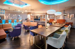 a restaurant with wooden tables and chairs and a cafeteria at Leonardo Hotel Wolfsburg City Center in Wolfsburg