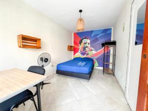 Zimmer mit einem blauen Bett und einem Gemälde an der Wand in der Unterkunft Casa Clandestina Guest House in Medellín