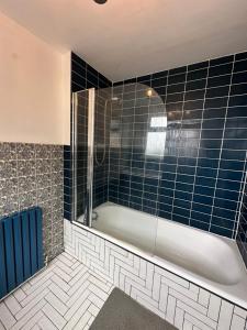 een badkamer met een bad en blauwe tegels bij Dartford Stay in Kent