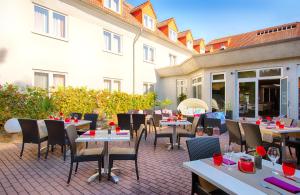 een patio met tafels en stoelen en een gebouw bij Leonardo Hotel Mannheim-Ladenburg in Ladenburg