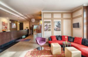 een woonkamer met een rode bank en een tafel bij Leonardo Hotel Köln Bonn Airport in Keulen