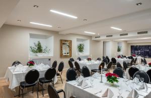 a conference room with tables and chairs with white tablecloths at Leonardo Royal Hotel Mannheim in Mannheim
