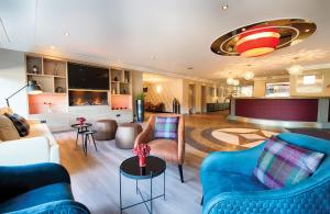 a living room with blue couches and chairs at Leonardo Hotel Hannover in Hannover