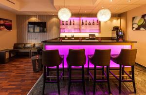 a bar in a hotel room with purple lighting at Leonardo Hotel Nürnberg in Nuremberg