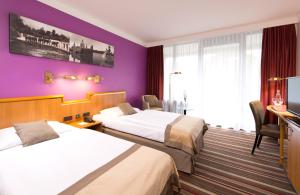 Habitación de hotel con 2 camas y paredes moradas en Leonardo Hotel Hannover en Hannover