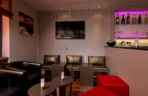 a bar with leather chairs and a red stool at Leonardo Hotel Nürnberg in Nuremberg
