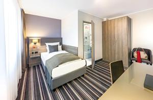 a hotel room with a bed and a desk at Leonardo Hotel Nürnberg in Nuremberg