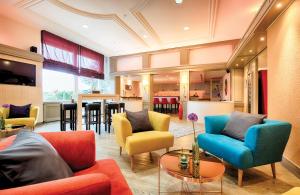 a living room with colorful chairs and a bar at Leonardo Hotel Karlsruhe in Karlsruhe