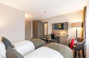 a hotel room with two beds and a television at Leonardo Hotel Nürnberg in Nuremberg