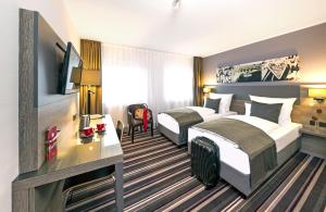 a hotel room with two beds and a television at Leonardo Hotel Nürnberg in Nuremberg