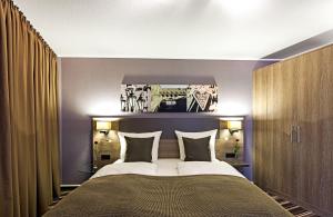 a bedroom with a large bed with two pillows at Leonardo Hotel Nürnberg in Nuremberg