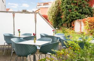 a patio with tables and chairs in a garden at Leonardo Hotel Nürnberg in Nuremberg