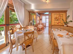 a dining room with tables and chairs and windows at Hotel Garni La Vigna in San Michele allʼAdige