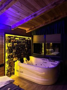 Sisorti süit bungalov في ريزي: حوض استحمام في غرفة بجدار حجري
