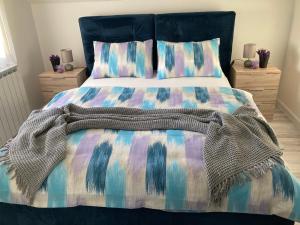 a bed with a colorful comforter and pillows at Sobe VaLux Valpovo in Valpovo