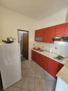 cocina con armarios rojos y nevera blanca en Apartment in Duce with sea view, balcony, air conditioning, W-LAN 5067-5, en Duće