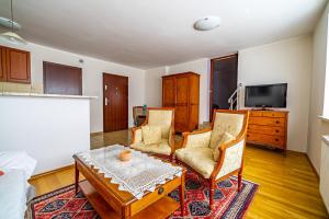 ein Wohnzimmer mit 2 Stühlen, einem Tisch und einem TV in der Unterkunft Casa Blanca in Jastarnia