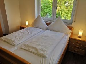 a bed with white sheets and pillows in a room with a window at Ferienzimmer Schneider in Herbstein