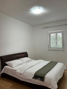 Cama en habitación blanca con ventana en Apartmani Andric, en Trebinje