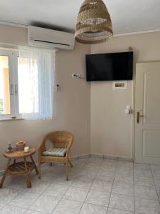 a living room with a chair and a tv on the wall at Melina's Apartments in Nea Kydonia