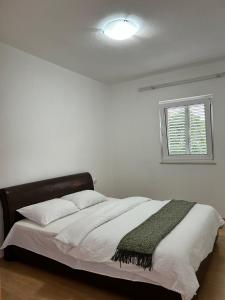 una camera da letto con un letto con lenzuola bianche e una finestra di Apartmani Andric a Trebinje