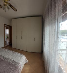 1 dormitorio con armarios blancos, 1 cama y ventana en B&B Traghetto, en Porto Garibaldi