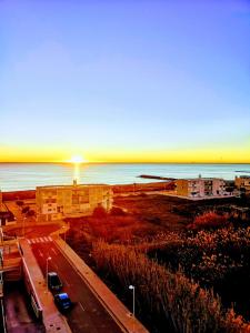 a sunset over the ocean and a road with cars at Beach,s House in Playa del Puig in La Torre
