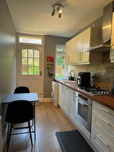 a kitchen with white cabinets and a table with chairs at Manor Court in London