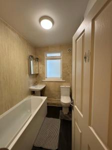 a bathroom with a tub and a toilet and a sink at Manor Court in London +22 photos