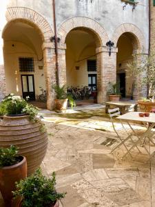une cour avec des arches, des tables et des plantes en pot dans l'établissement Casa Valeria - Guest House Centro Storico, à Fano