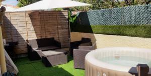 una bañera de hidromasaje en un patio trasero con sombrilla en Maison T2 proche mer jardin spa jacuzzi et parking en Six-Fours-les-Plages