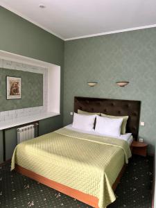 ein Schlafzimmer mit einem Bett mit einer grünen Wand in der Unterkunft RANDEVU in Schytomyr