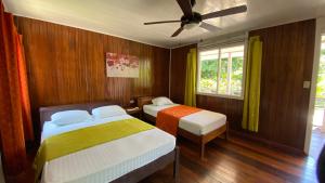 1 dormitorio con 2 camas y ventilador de techo en La Baula Lodge en Tortuguero