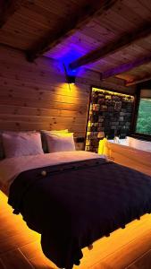 Sisorti süit bungalov في ريزي: غرفة نوم بسرير كبير مع اضاءة ارجوانية