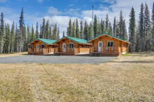 a log cabin in a field with trees in the background at Charming Soldotna Cabin Near Kenai River Fishing! in Soldotna