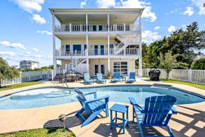 a house with a swimming pool and blue chairs at Sunset Villa in Holden Beach