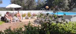 two people sitting under an umbrella next to a swimming pool at Villa Ewa in Págoi