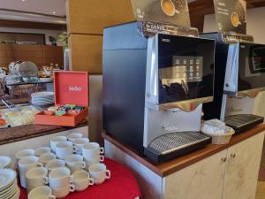 una cafetera en un mostrador junto a las tazas en Continental Inn, en Foz do Iguaçu