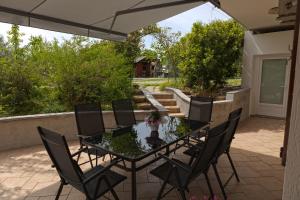a patio with a glass table and chairs on a patio at IL LILLA in Ankaran