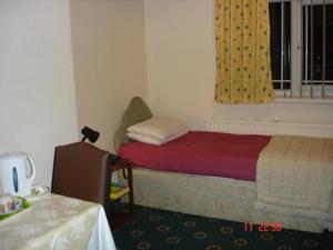 1 dormitorio con cama, ventana y mesa en Victoria Park Hotel, en Mánchester