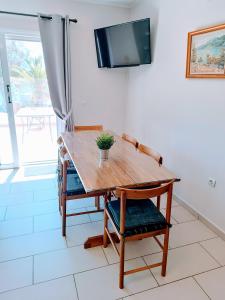 Hermione Port Luxury Residence في إرميوني: طاولة وكرسي خشبي مع تلفزيون على جدار