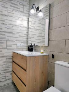 a bathroom with a sink and a toilet and a mirror at Apartamento en el barrio marítimo del Serrallo in Tarragona