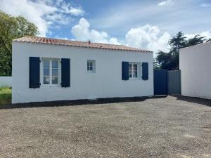 a white house with black shutters on a driveway at Maison de vacances - Classé meublé de tourisme 3 étoiles in L'Ile d'Yeu