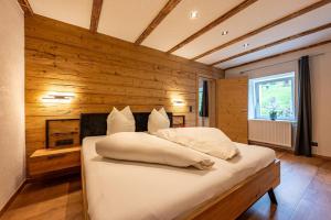 a bed in a room with a wooden wall at Gasthaus Traube in Bichlbach