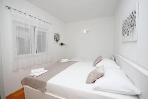a white bedroom with a large white bed with two pillows at Apartmani Šulenta in Tučepi
